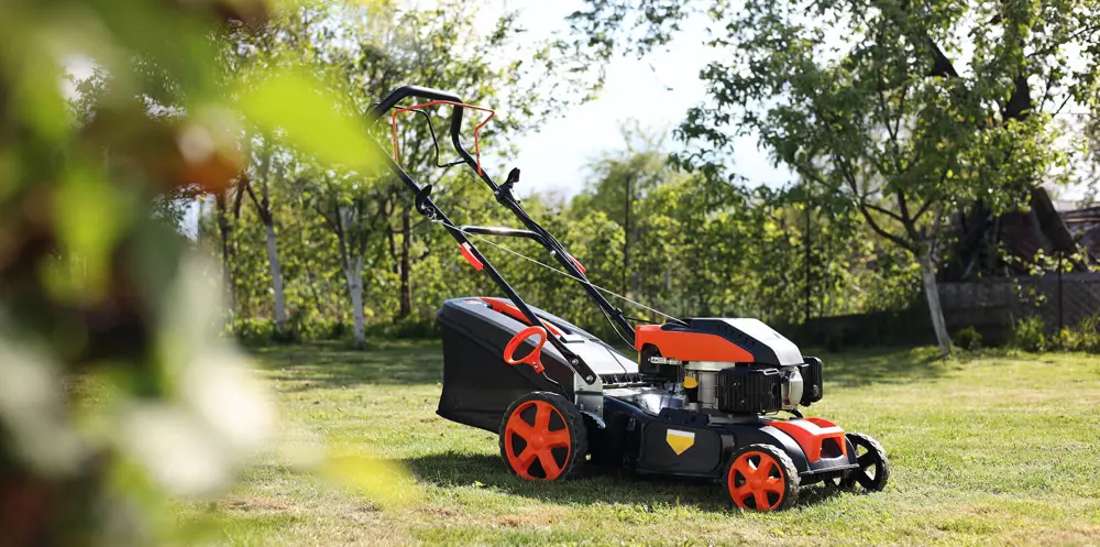 Электрическая газонокосилка в саду.
