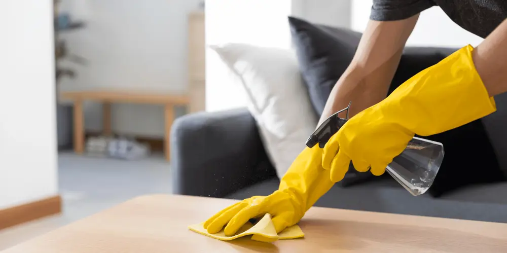 Женщина моет стол.