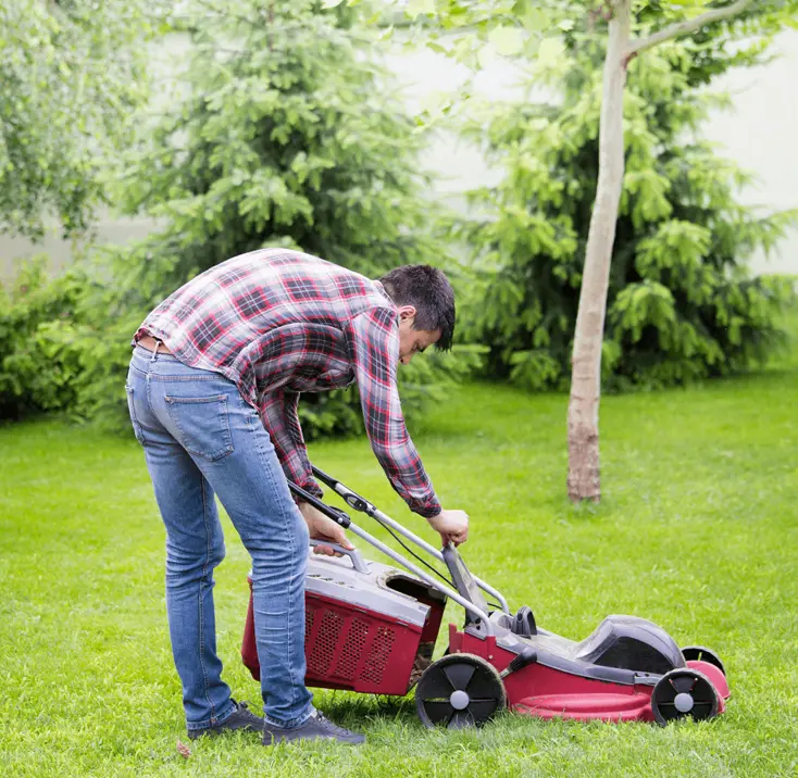 Мужчина настраивает газонокосилку.