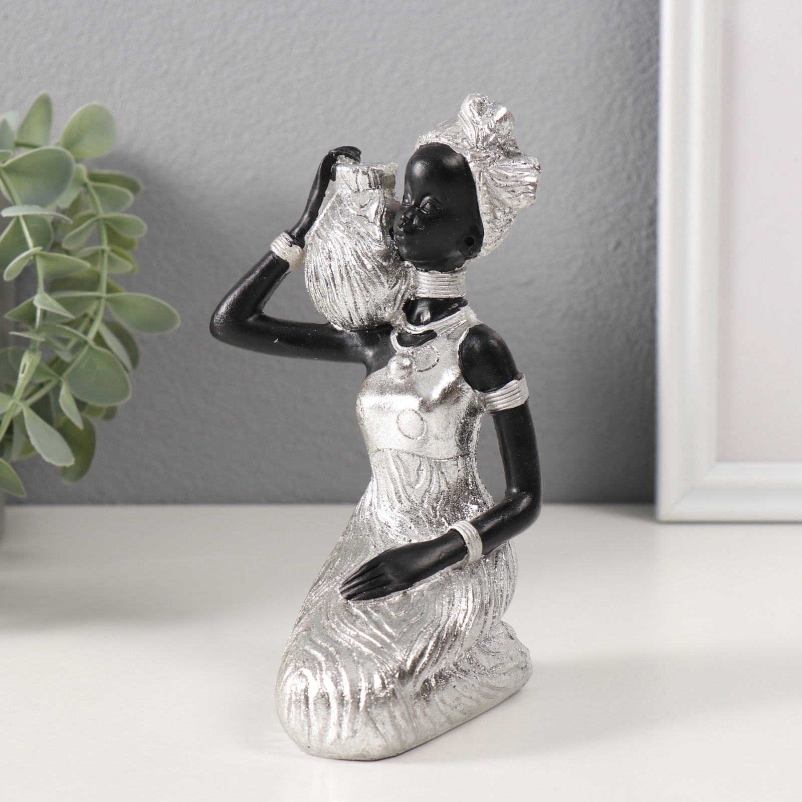 Изображение товара Сувенир полистоун Африканка в платье с листьями с кувшином сидит серебро 105х9х16 см 10323458